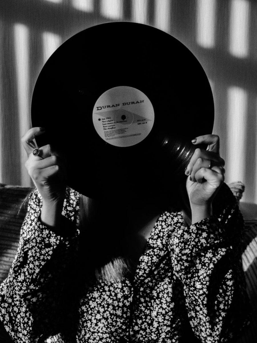 unrecognized woman covering her face behind black vinyl record