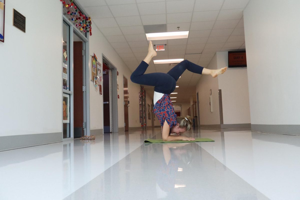 Señora Traci Lerner takes a moment to re-center by practicing her arm balances in the hallway outside her classroom. Photo credit Alex Piazza '28